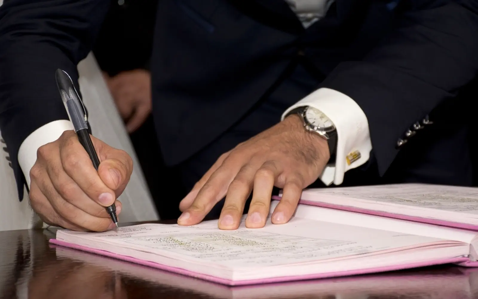 A person in a suit signing a document